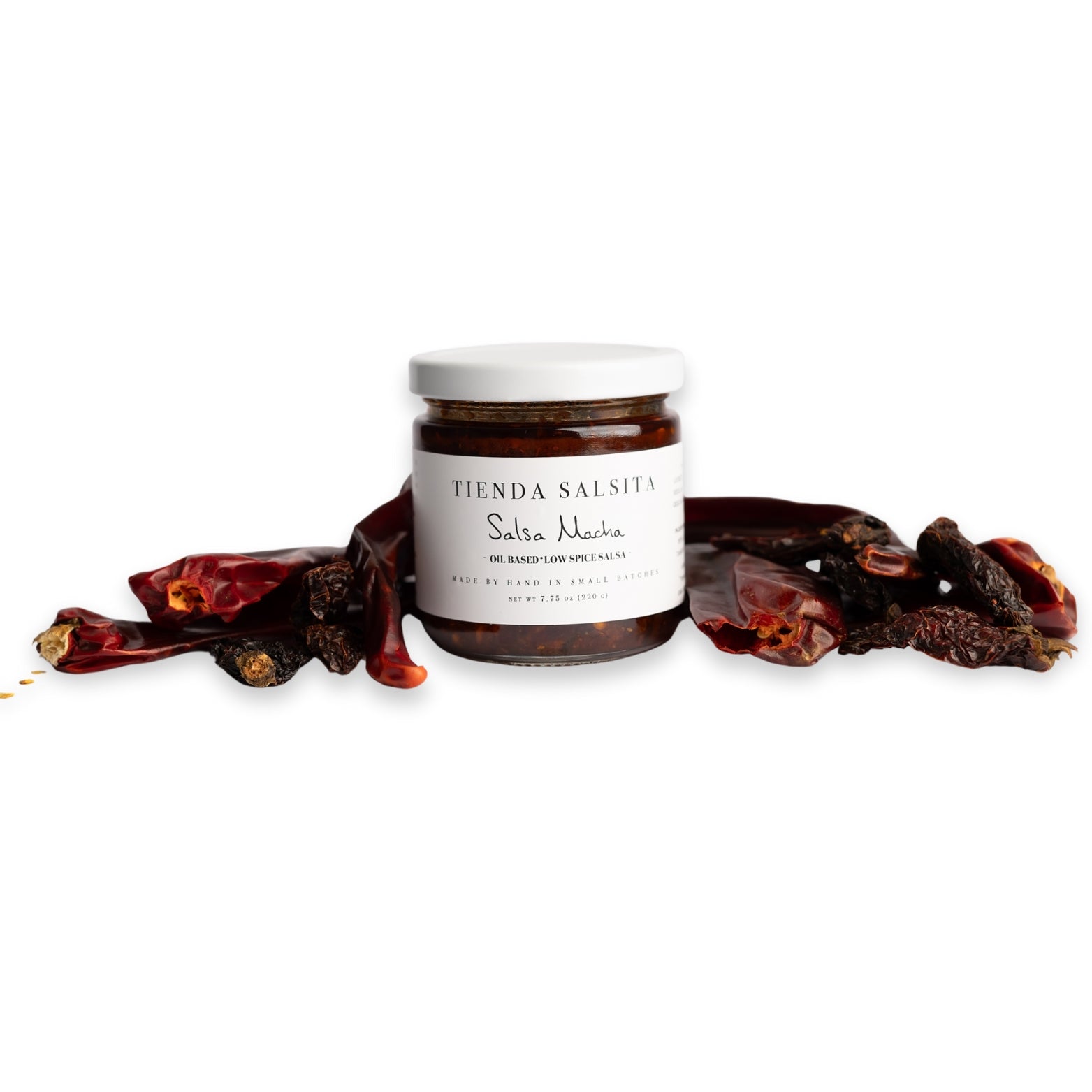 Jar of Thenda Salsita salsa with dried red chilies on a white background