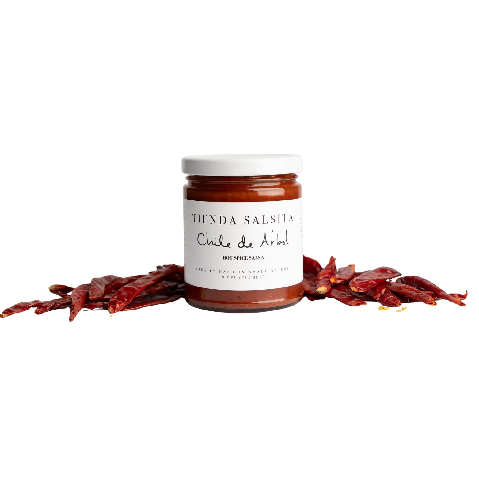 Jar of hot sauce with dried chilies on a white background