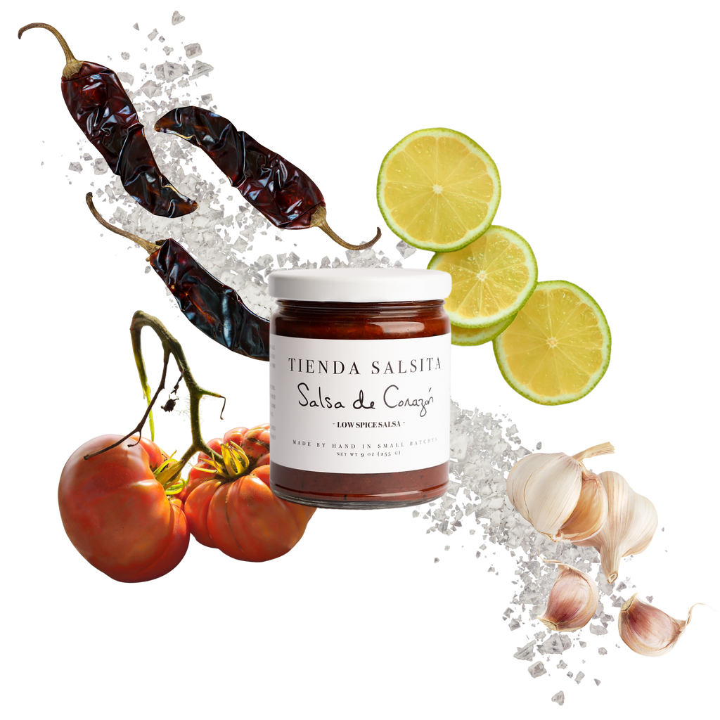 Jar of 'Tienda Salsita' salsa surrounded by chili peppers, tomatoes, and limes on a white background