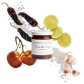 Jar of 'Tienda Salsita' salsa surrounded by chili peppers, tomatoes, and limes on a white background