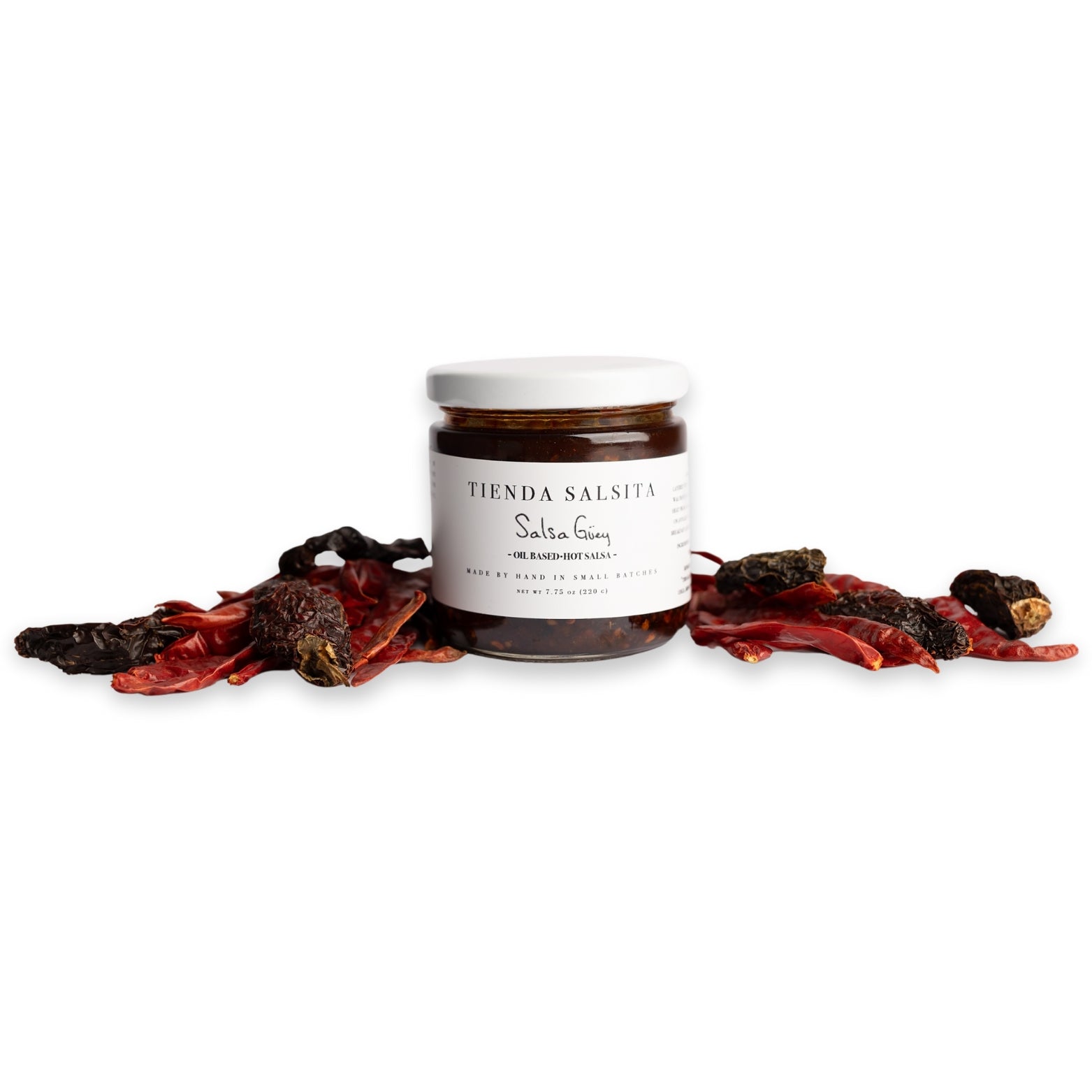 Jar of salsa with dried red peppers on a white background