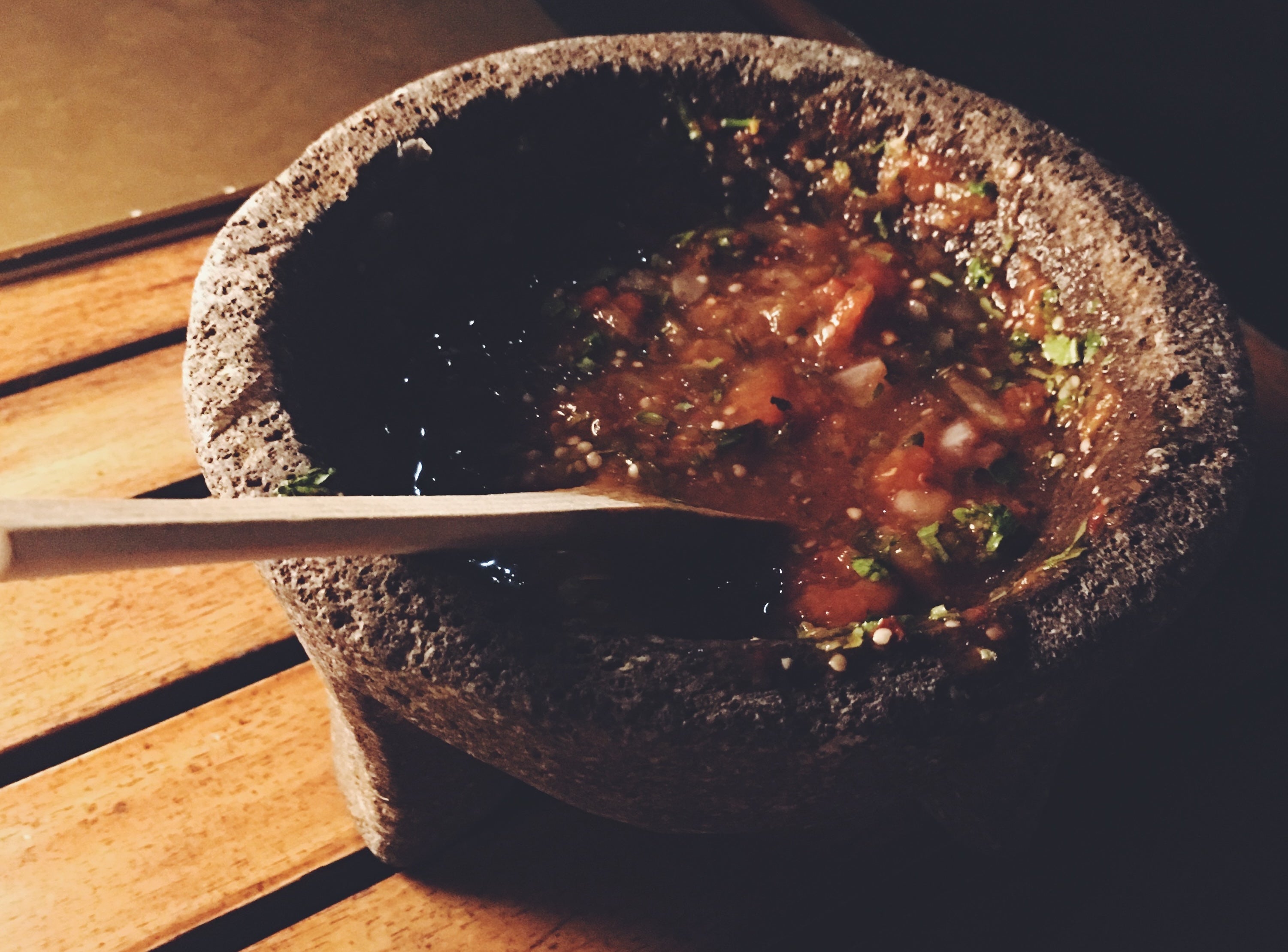Molcajete with salsa on a wooden surface