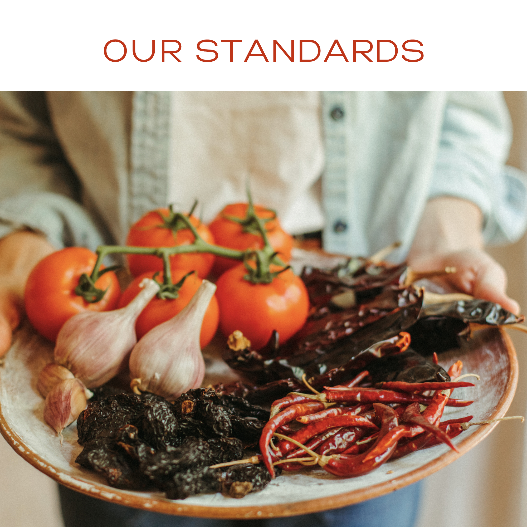 Platter of fresh vegetables including tomatoes, garlic, and chili peppers with 'Our Standards' text above.